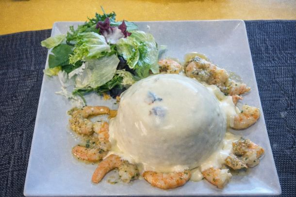 Gambas salteadas en salsa cremosa acompañadas de ensalada verde variada servidas en plato cuadrado blanco